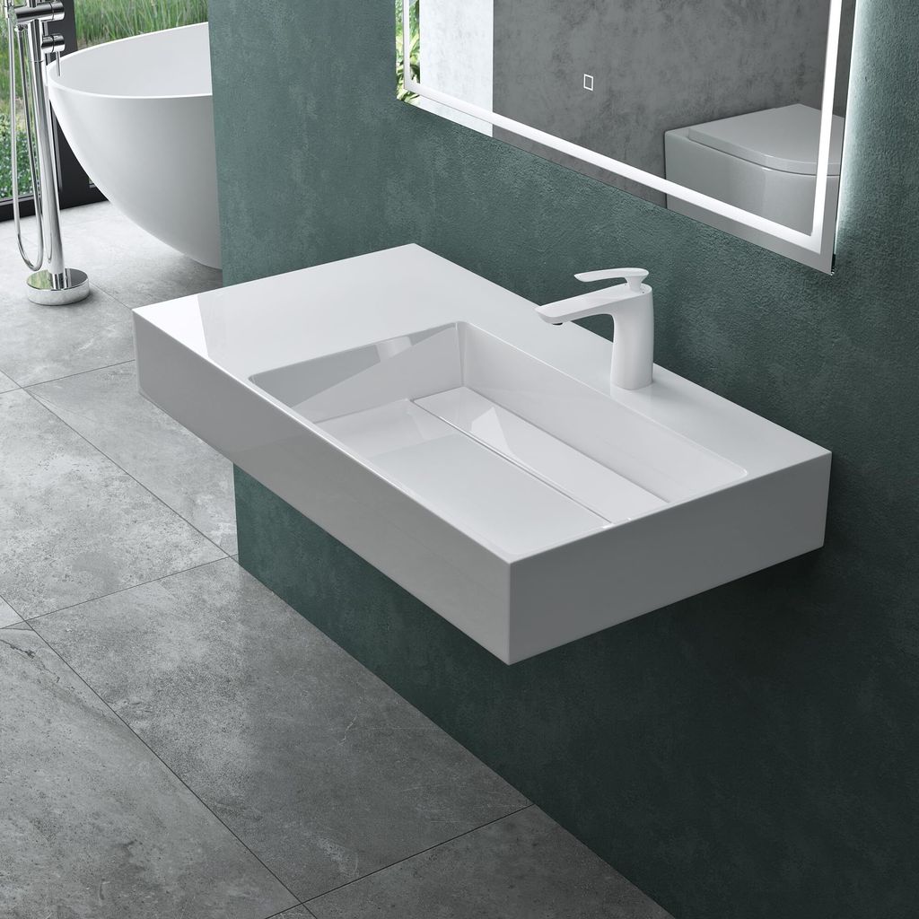 A modern bathroom with a wall-mounted sink and a bathtub visible in the background.