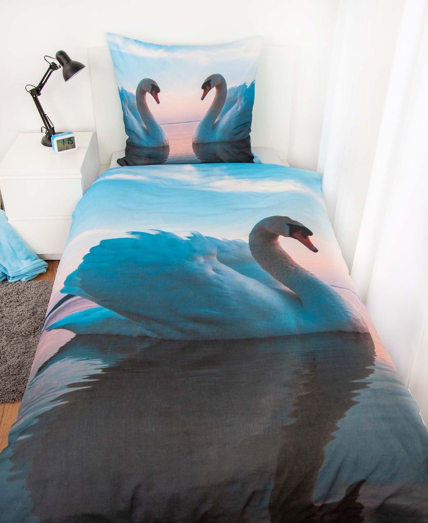 A bed with bedding featuring a swan print.