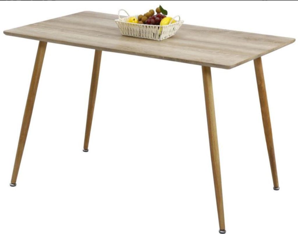 A wooden dining table with a basket of fruit on it.