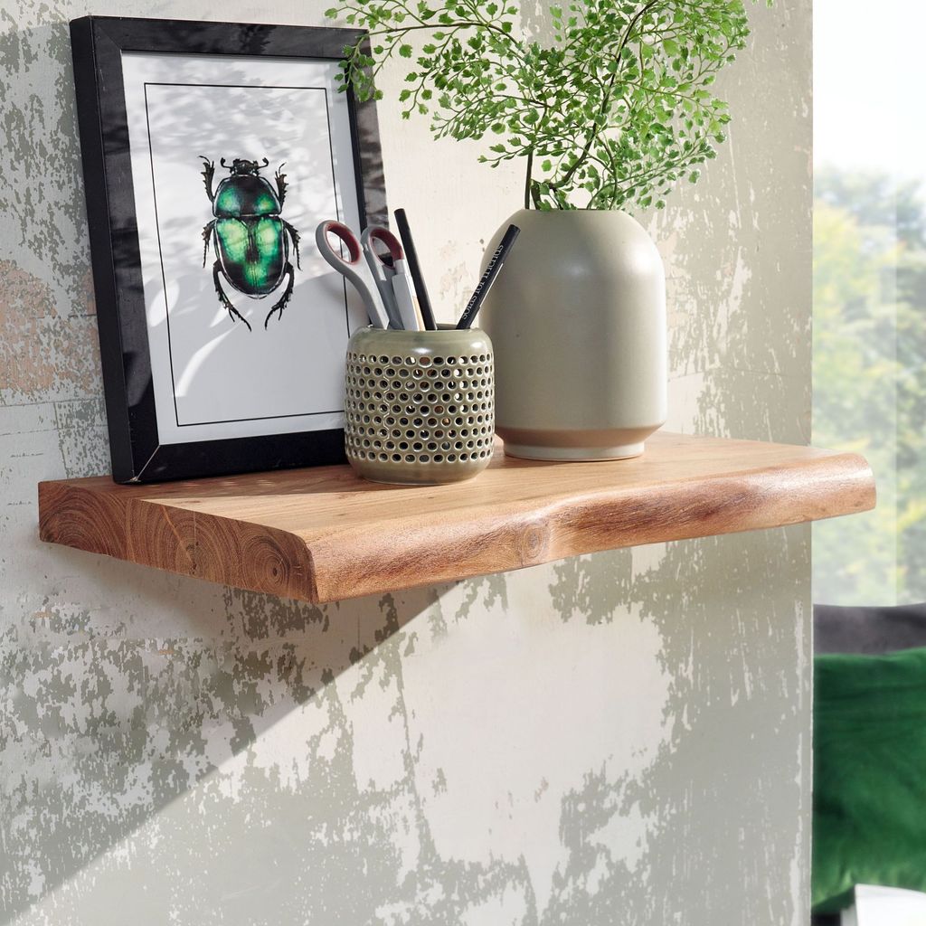 A wooden shelf mounted on a textured wall, decorated with a framed picture of a beetle, a pen holder with writing utensils, and a vase with a plant.