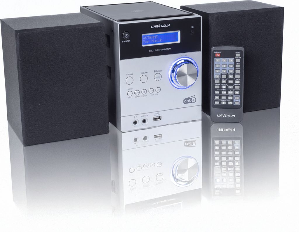 A stereo system with two speakers and a remote control, displayed on a reflective white surface.
