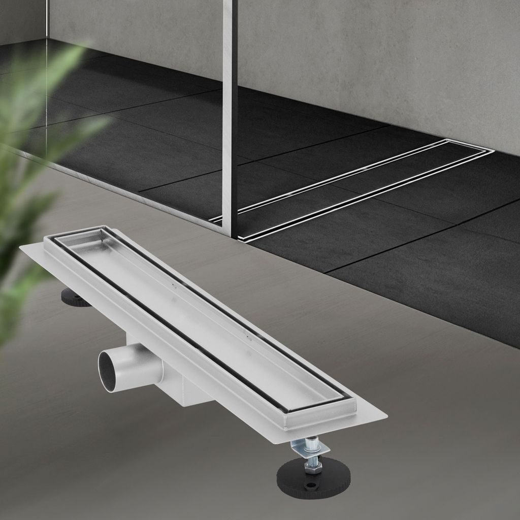 A linear shower drain is shown in the foreground, with a tiled shower area in the background.