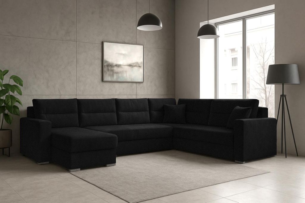A black sectional sofa with an ottoman is placed in a modern living room with concrete-look walls and a large window.