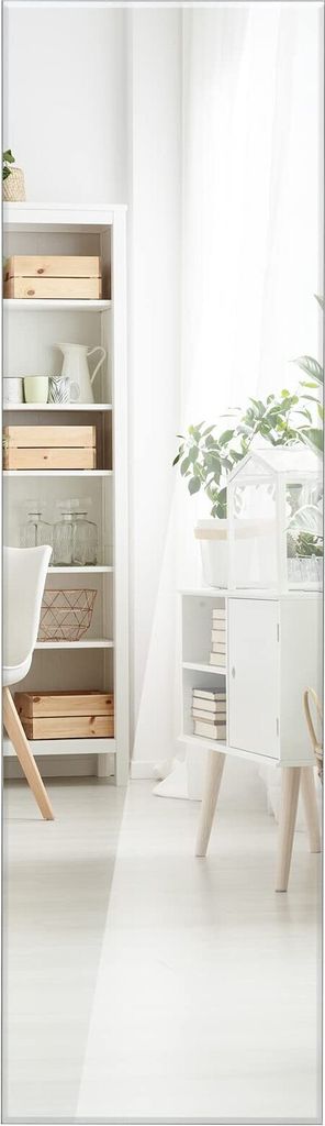 A bright, minimalist room with a white bookshelf and a white cabinet with wooden legs.