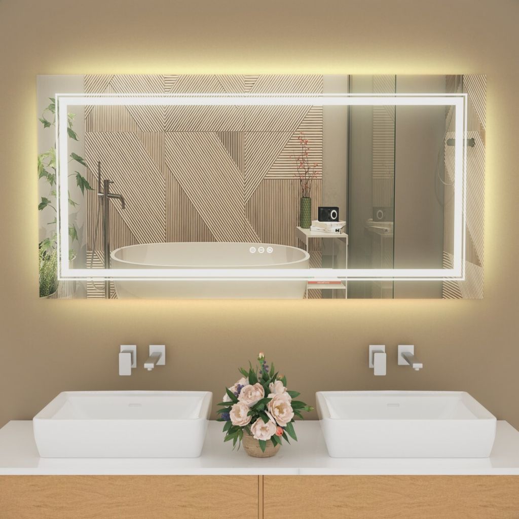 A modern bathroom vanity with two sinks, a large illuminated mirror, and a floral arrangement.