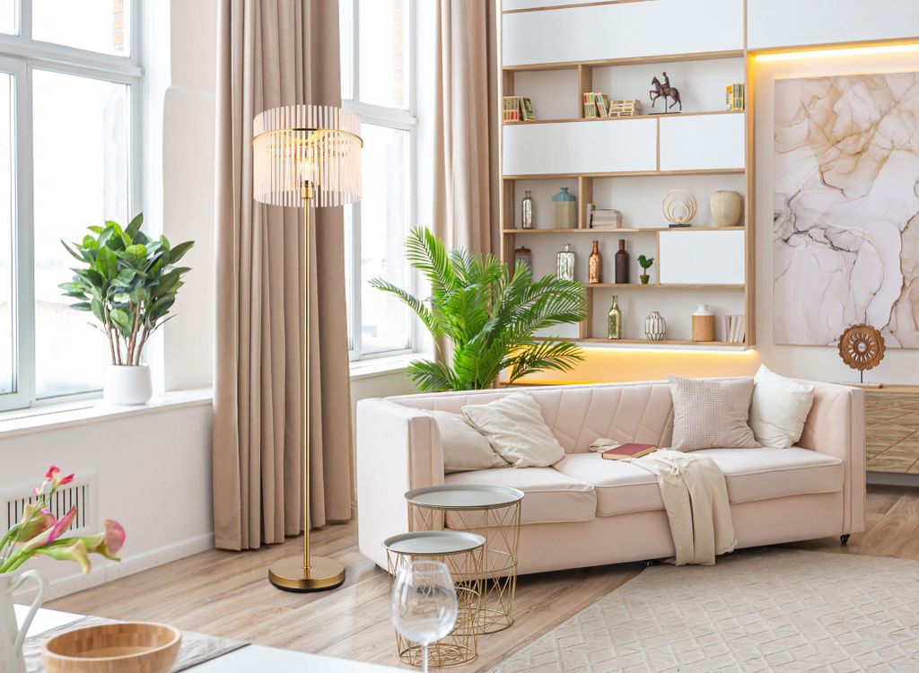 A modern living room with a sofa, shelves, and a floor lamp.