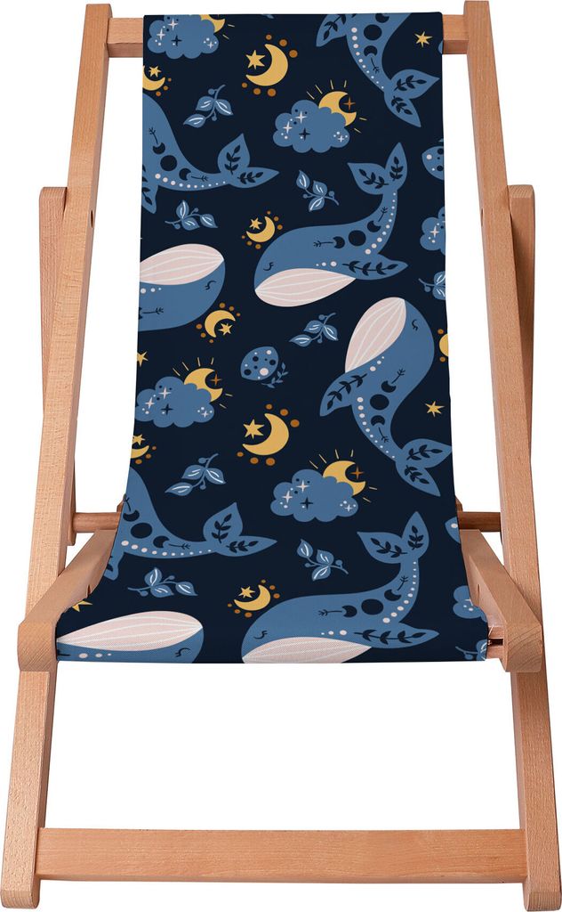 A wooden deck chair with a dark blue fabric seat featuring a pattern of whales, moons, and stars.
