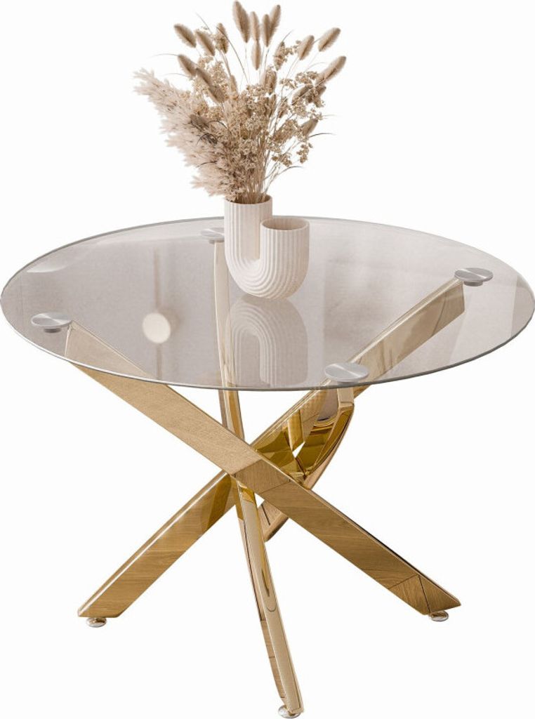 A round glass-top coffee table with a gold chrome base, decorated with a vase of dried flowers.