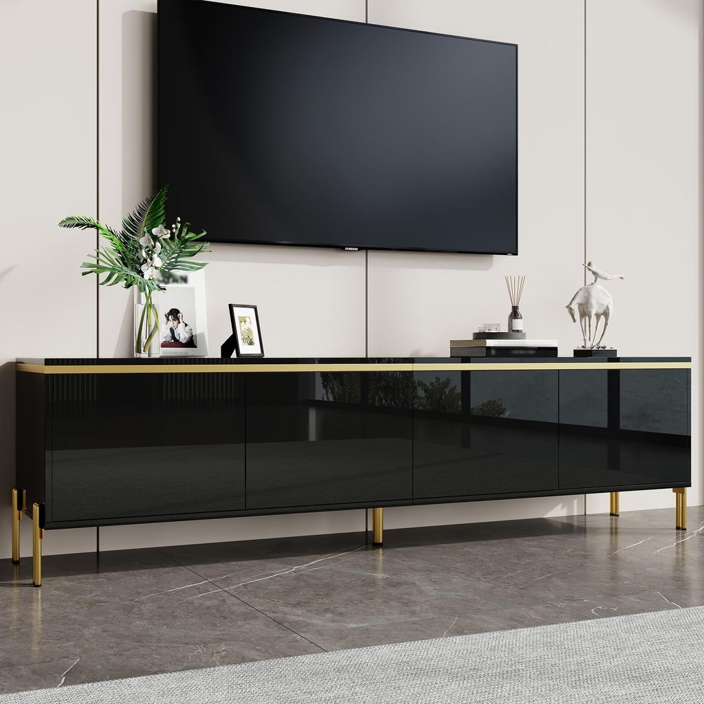 A black TV cabinet with gold accents and legs, with a TV mounted above it.