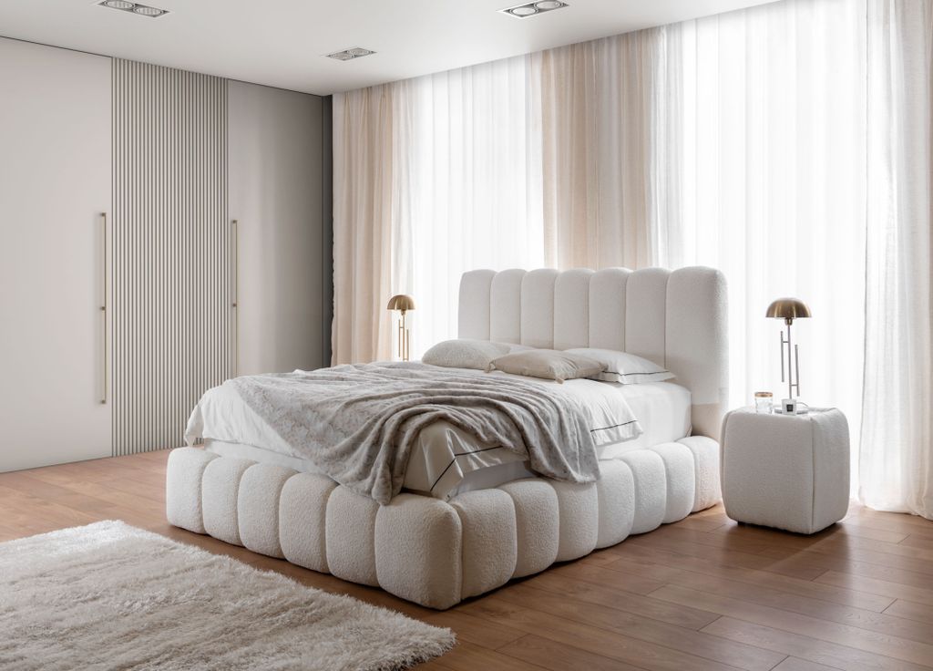 A bedroom scene with a large white bed, bedside table, and wardrobe.
