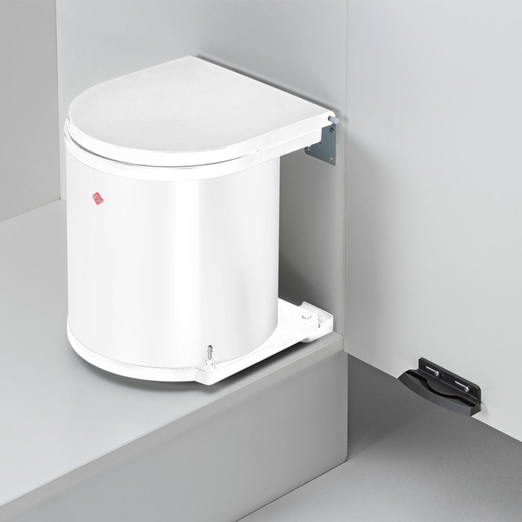 A white trash can with a lid is mounted on a wall in a corner.