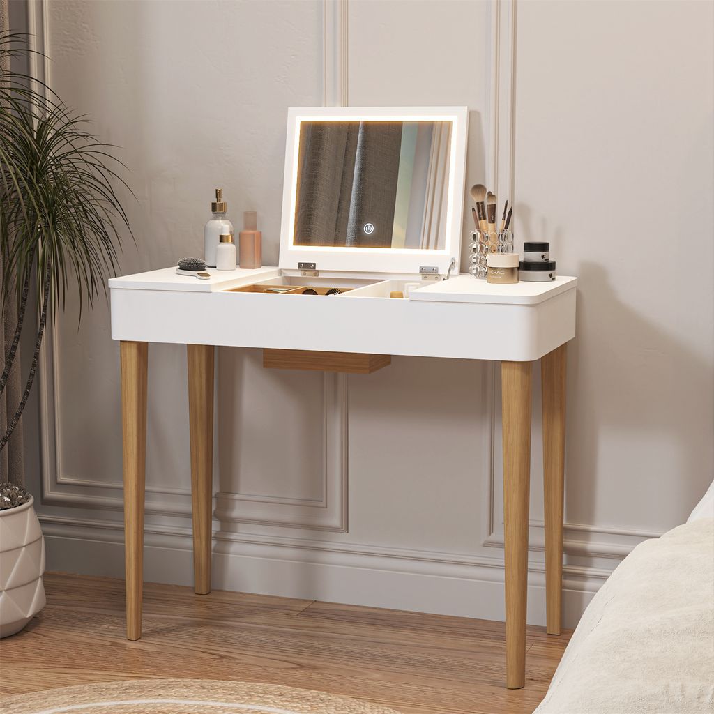 A white vanity table with a lighted mirror and makeup products is set up in a bedroom.