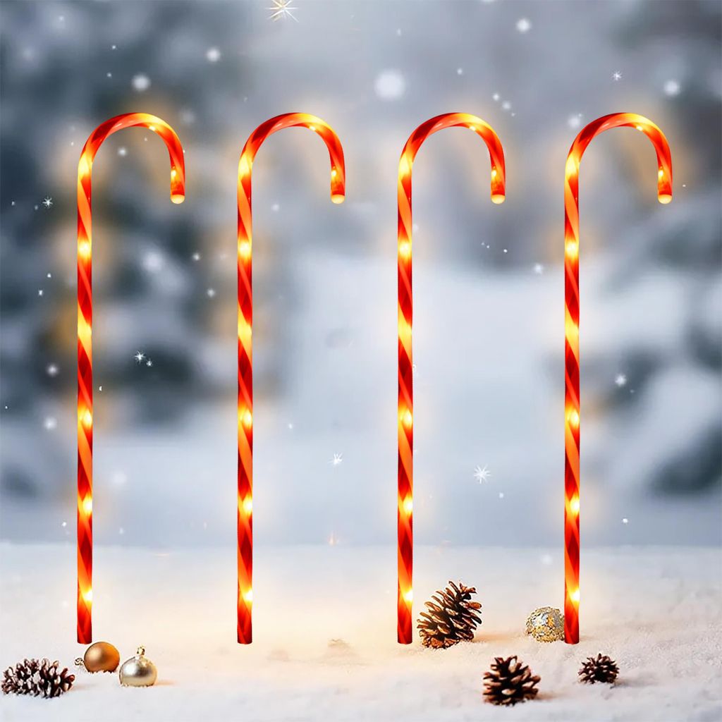 Four illuminated candy canes stand in the snow with pinecones and ornaments.