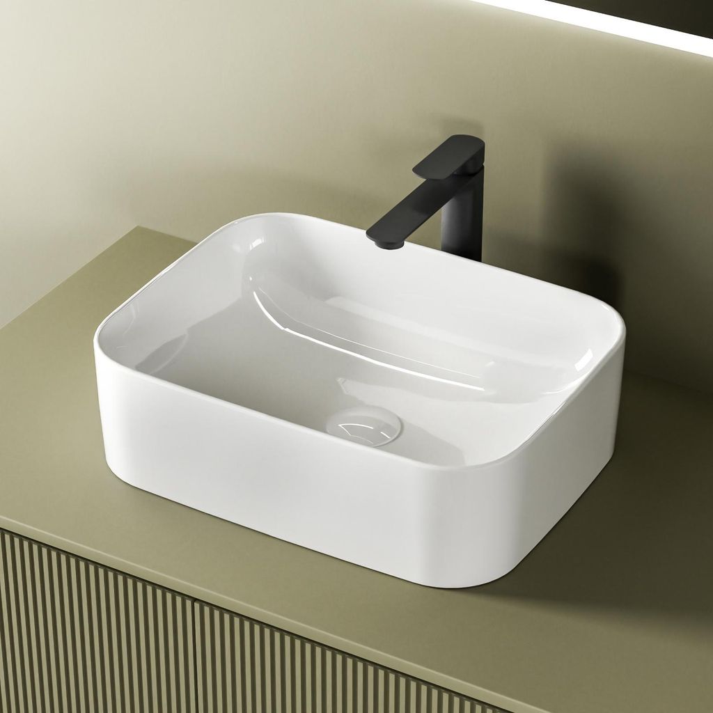 A white ceramic vessel sink with a black faucet is shown on a light green countertop.