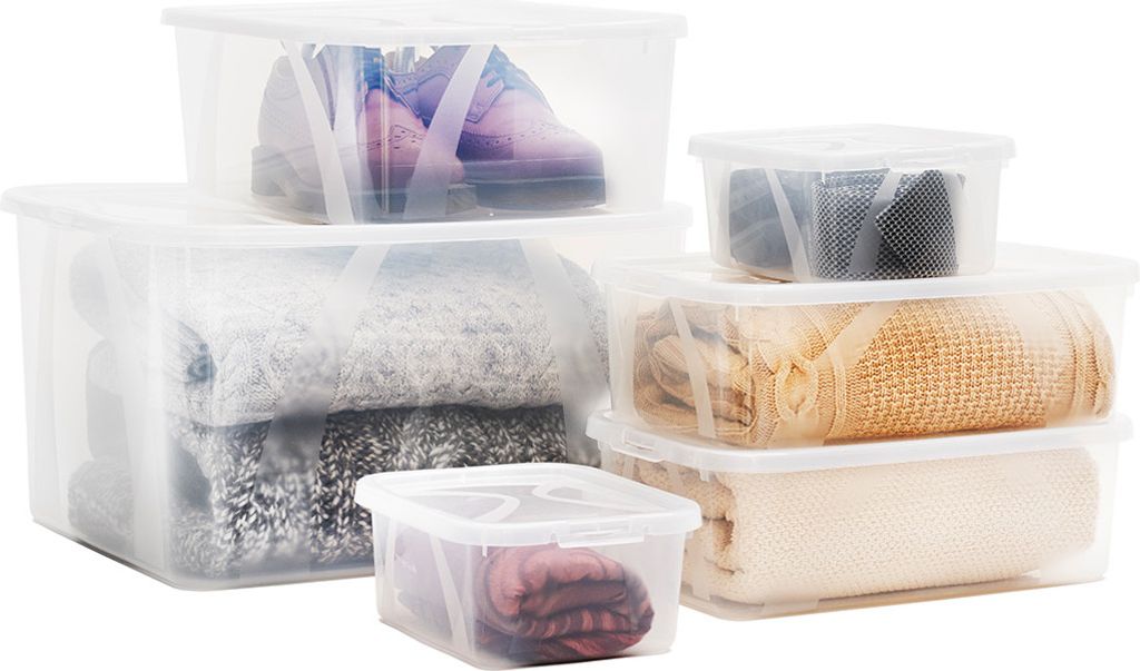 Several clear plastic storage boxes of various sizes are stacked and arranged, containing folded textiles like blankets and sweaters, and a pair of shoes.