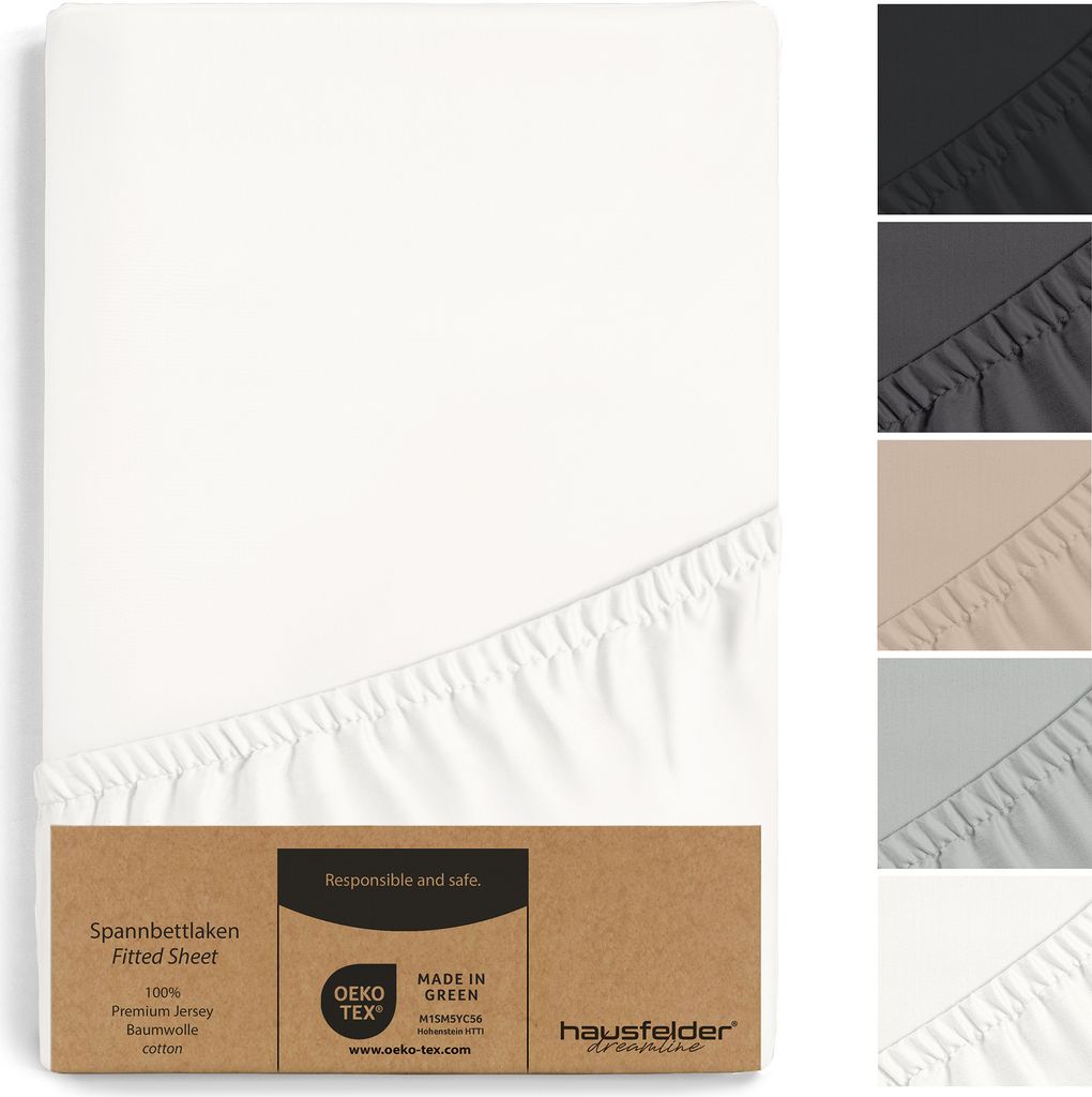 A white fitted sheet is shown folded and partially unfolded, with a cardboard tag attached to the bottom corner. Several other colors of the fitted sheet are displayed in small stacked images on the right side.