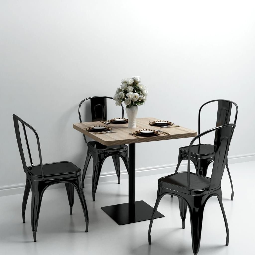 A square dining table with four chairs set up in a room with a white wall.