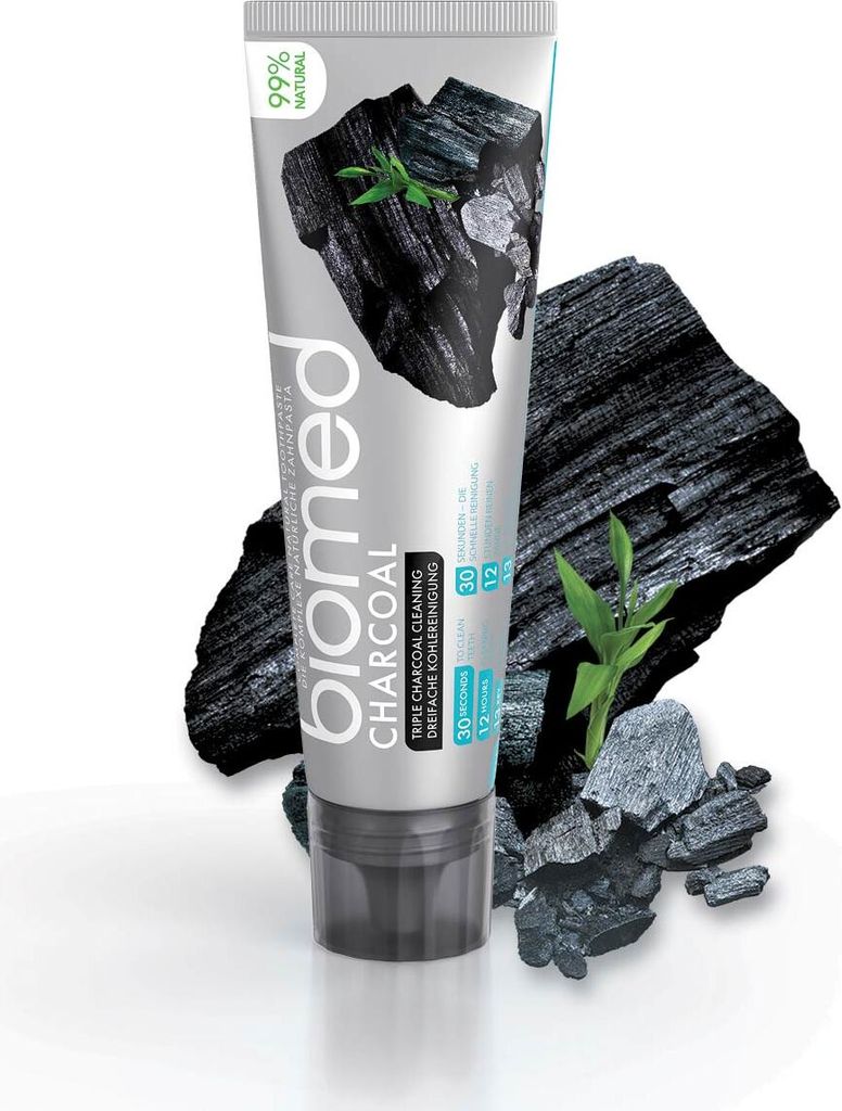 A tube of BIOMED CHARCOAL toothpaste is shown with charcoal pieces and green leaves.