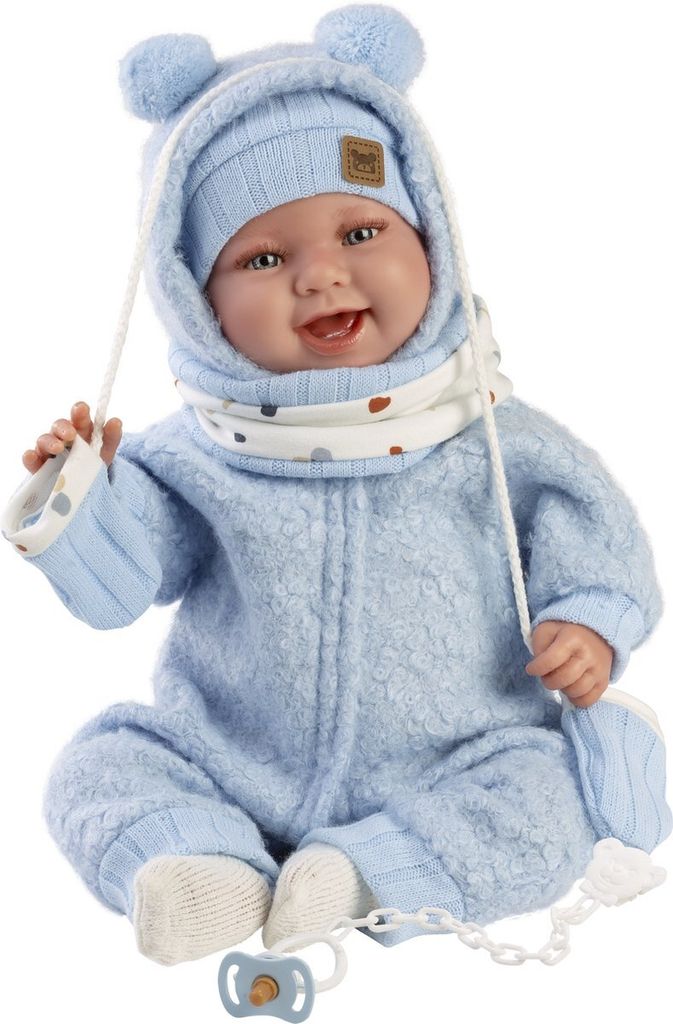 A baby doll dressed in a blue outfit with a hat and scarf, sitting down.