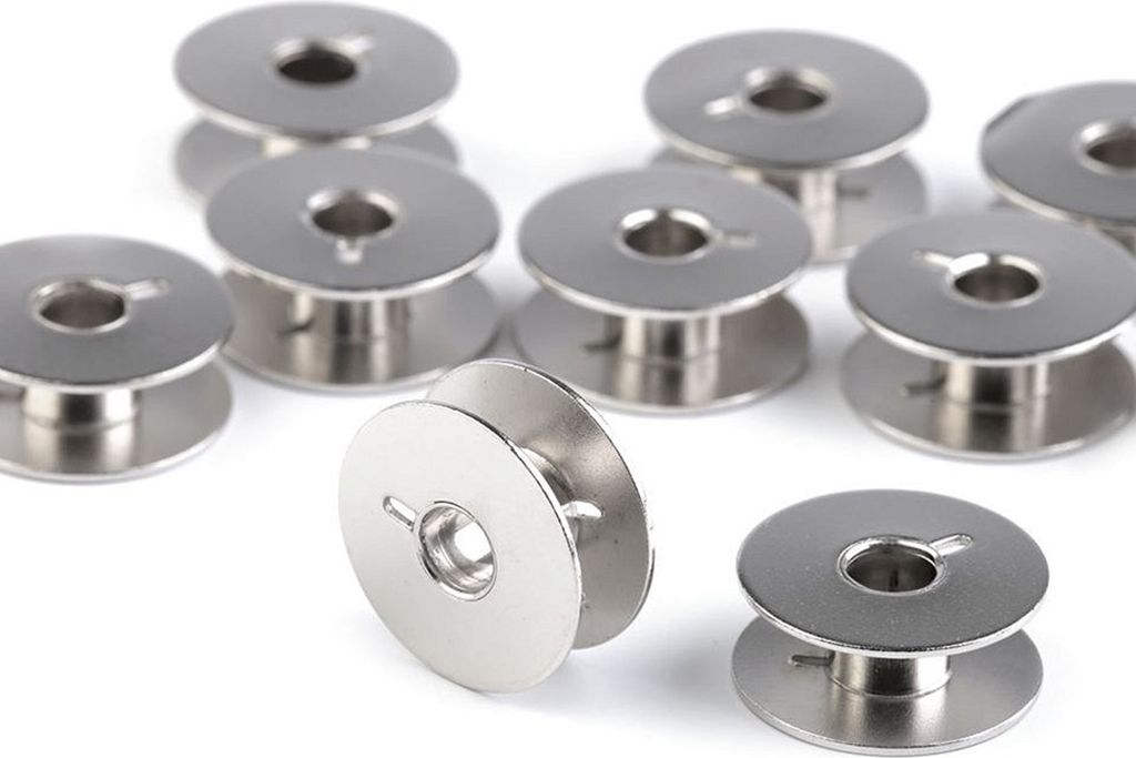A group of silver sewing machine bobbins on a white background.