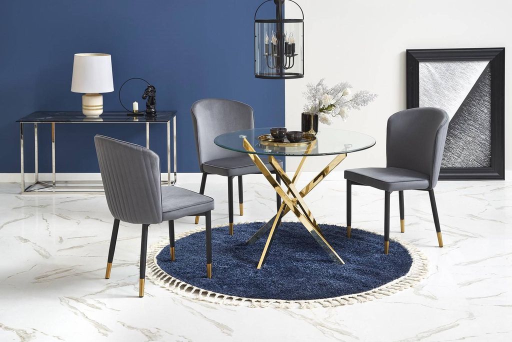 A dining set with a round glass table and four chairs, placed on a blue rug.