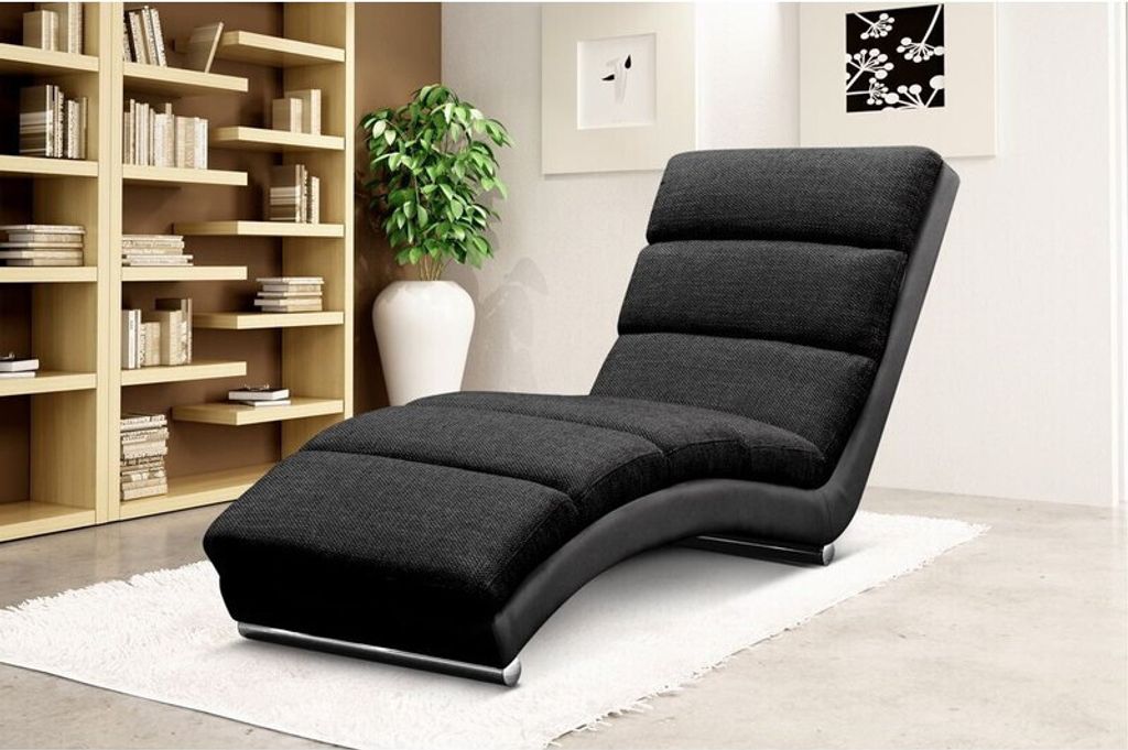 A modern living room with a chaise lounge in the foreground and a bookshelf in the background.