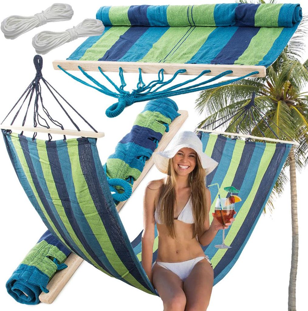 A woman in a bikini relaxing in a hammock with a drink, with a palm tree in the background.