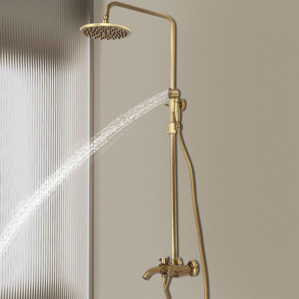 A gold-colored shower system with a rainfall showerhead and handheld showerhead is shown in use, with water spraying from the showerhead.