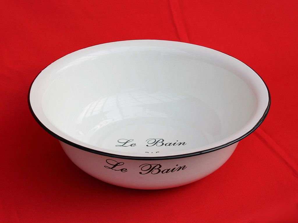 A white enamel basin with black trim sits on a red surface.