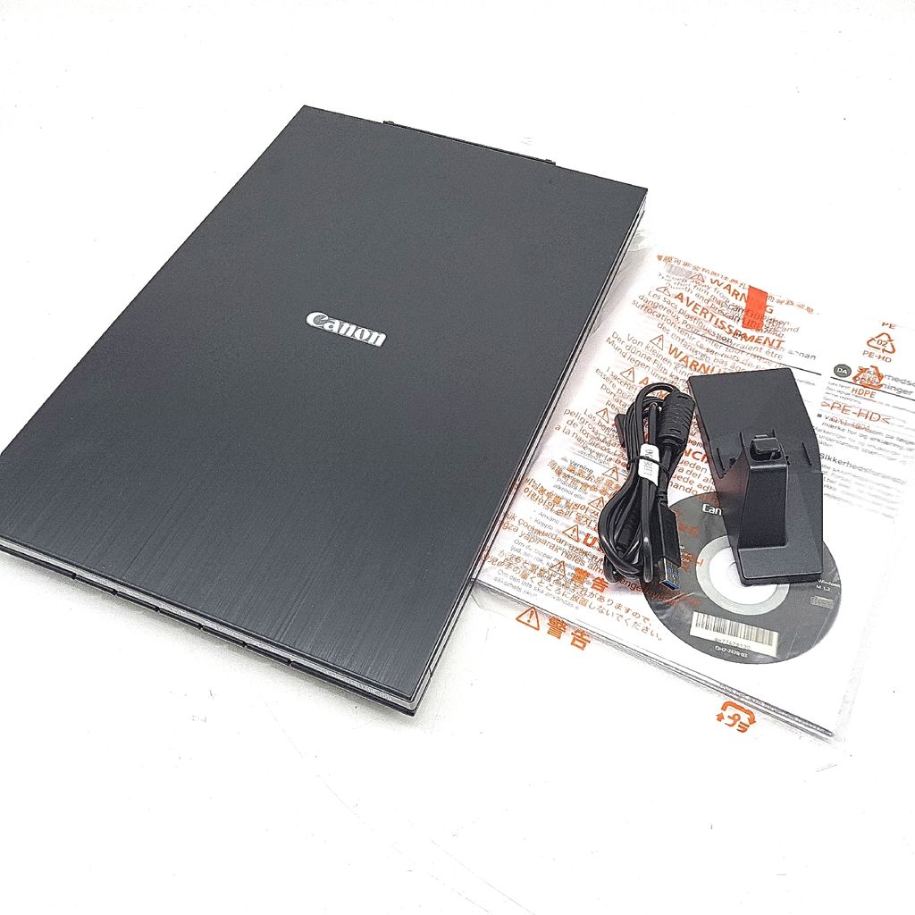 A Canon flatbed scanner and its accessories are laid out on a white background.