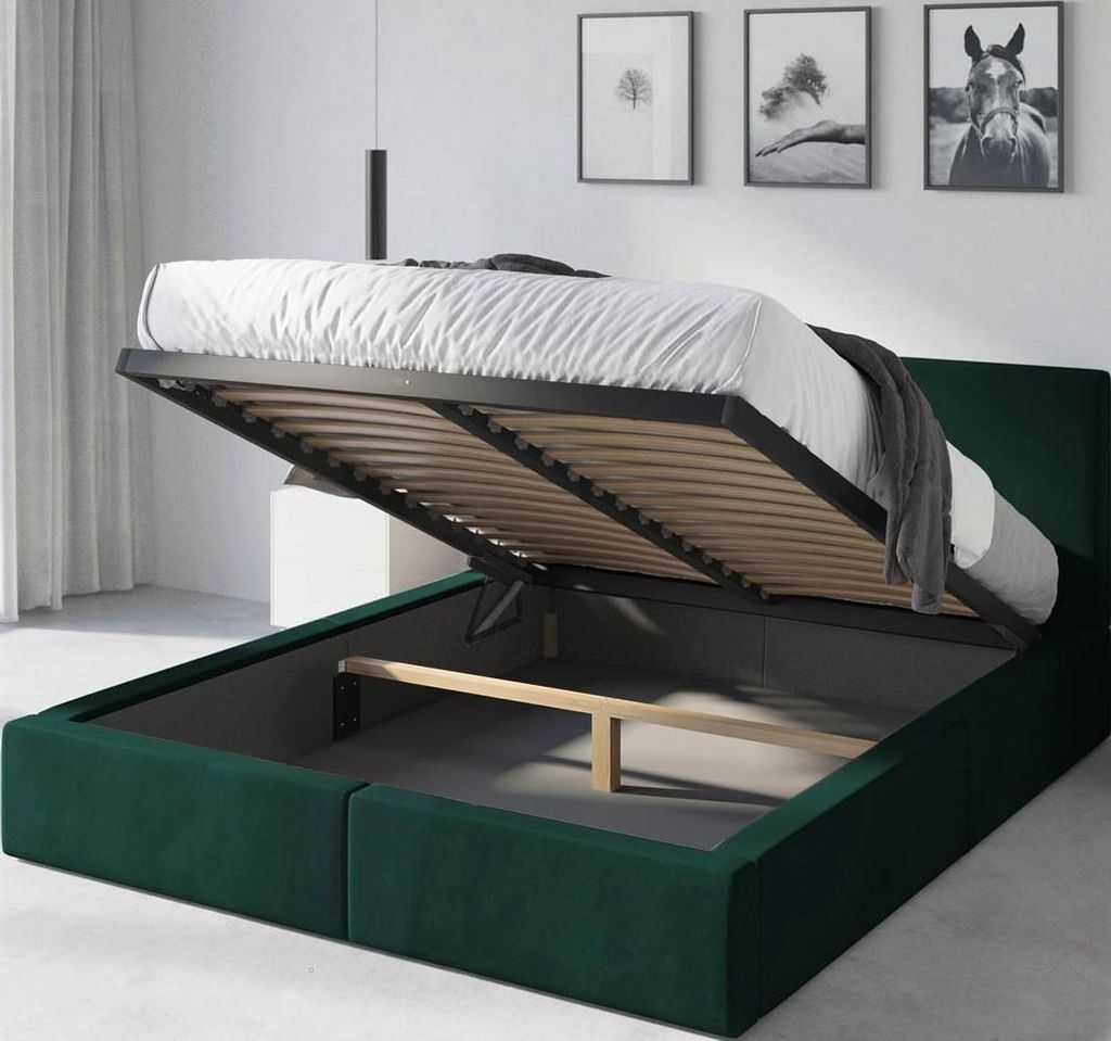 A green upholstered bed frame with the mattress and slatted base lifted to reveal the storage compartment underneath.