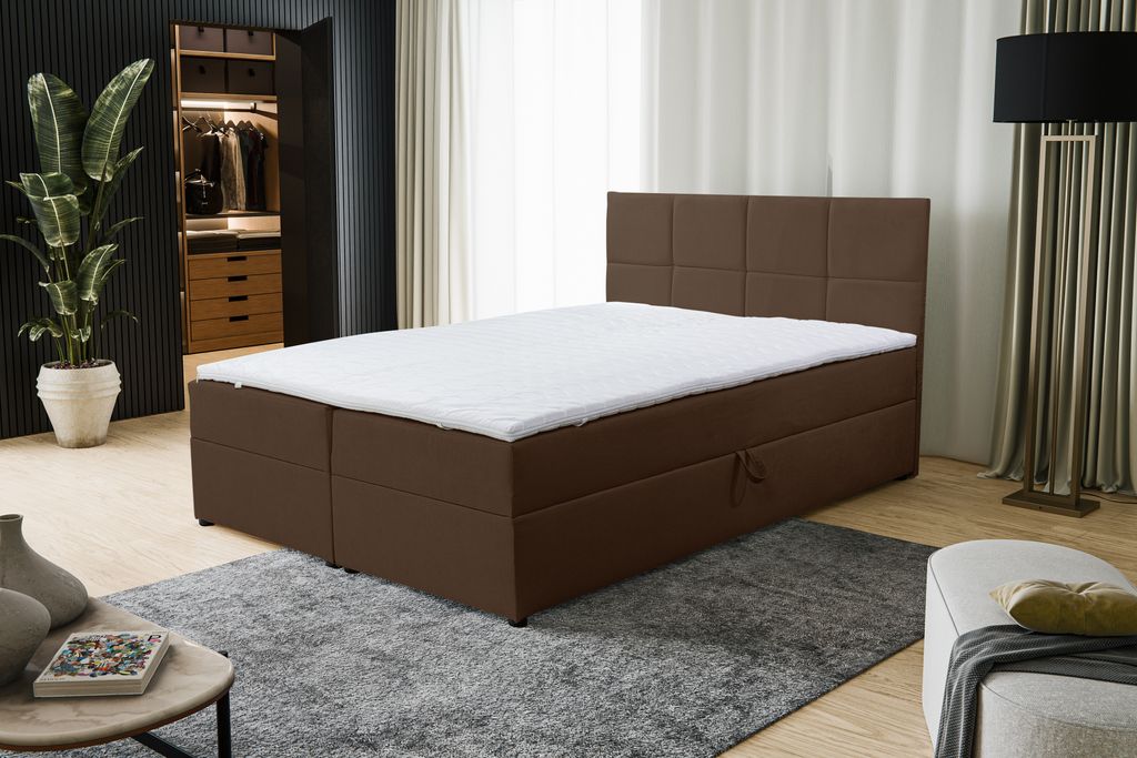 A bedroom scene with a brown boxspring bed as the main focus, a plant in the background, and a floor lamp.