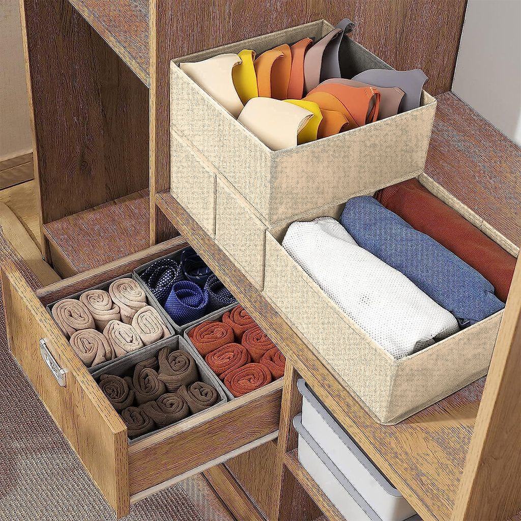Storage boxes and drawer organizers filled with rolled-up clothing items like socks and ties, placed inside a wooden closet or shelving unit.