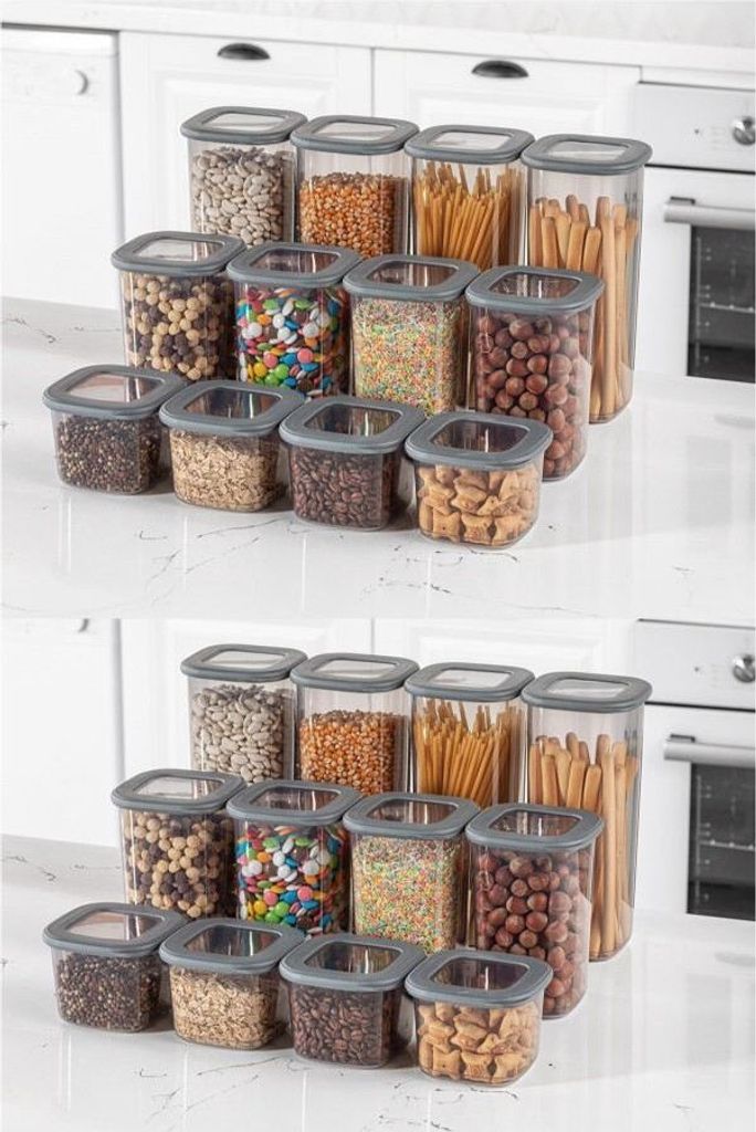 Two rows of clear plastic food storage containers filled with various food items and snacks, arranged on a white countertop.