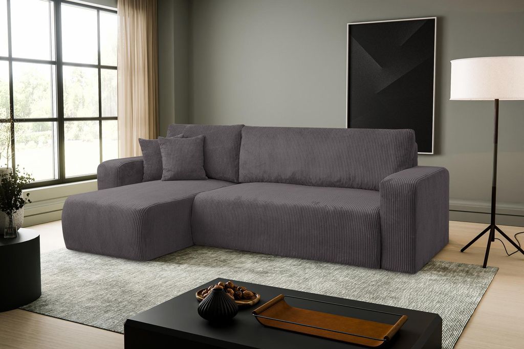 A dark gray sectional sofa is shown in a well-lit living room with large windows.