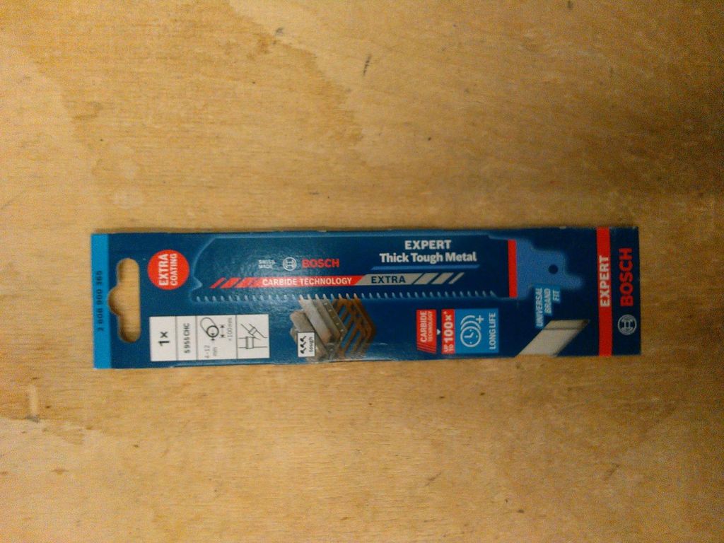 A Bosch Expert Thick Tough Metal reciprocating saw blade in its packaging, lying on a wooden surface.