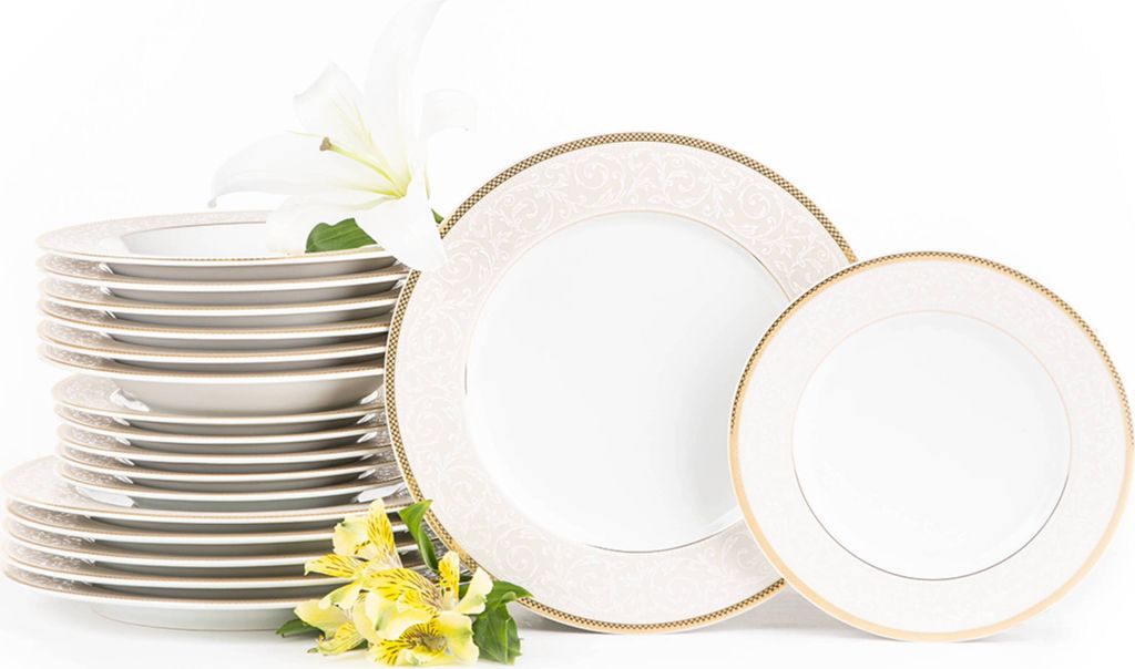 A stack of white dinner plates with gold trim and two decorative plates, accompanied by white and yellow flowers, on a white background.