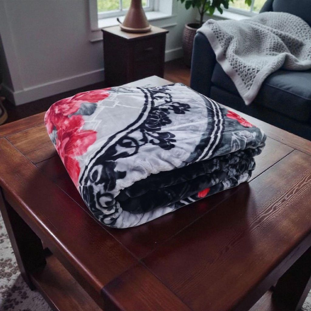 A folded blanket with a floral pattern is placed on a wooden coffee table in a living room setting.