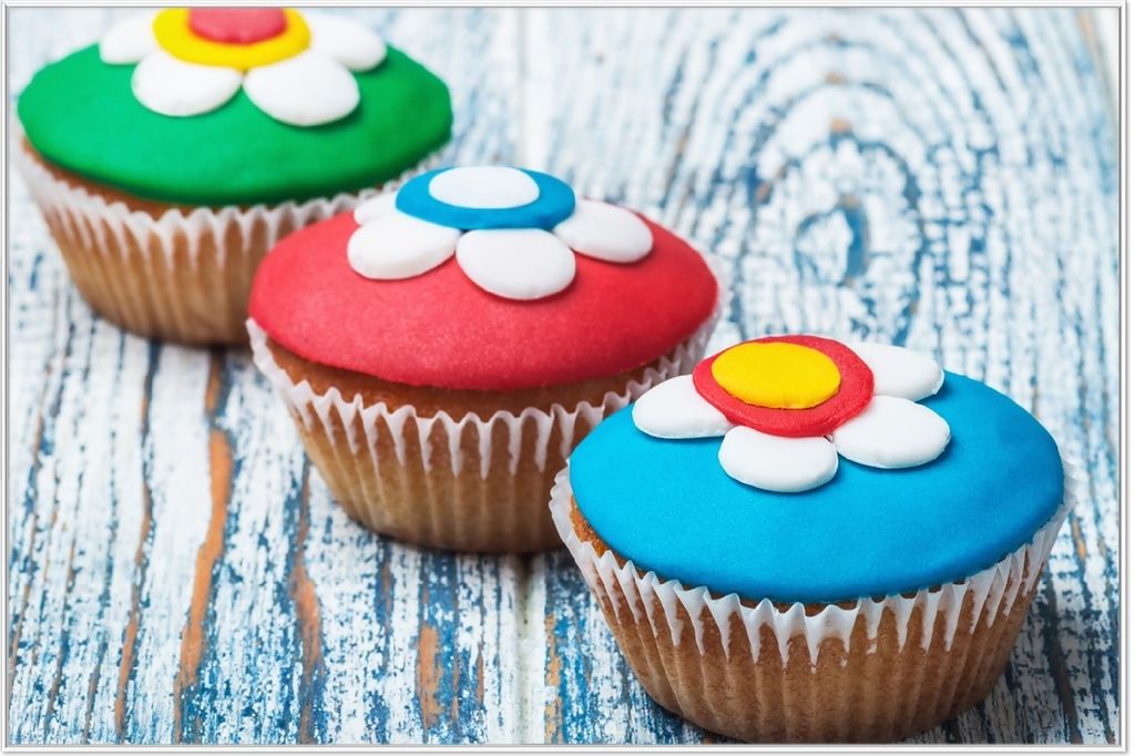 Wallario Wandbild Bunte Muffins - alter Holztisch - Stillleben, Größe: 61 x 91,50 cm, Poster mit weißem Aluminiumrahmen