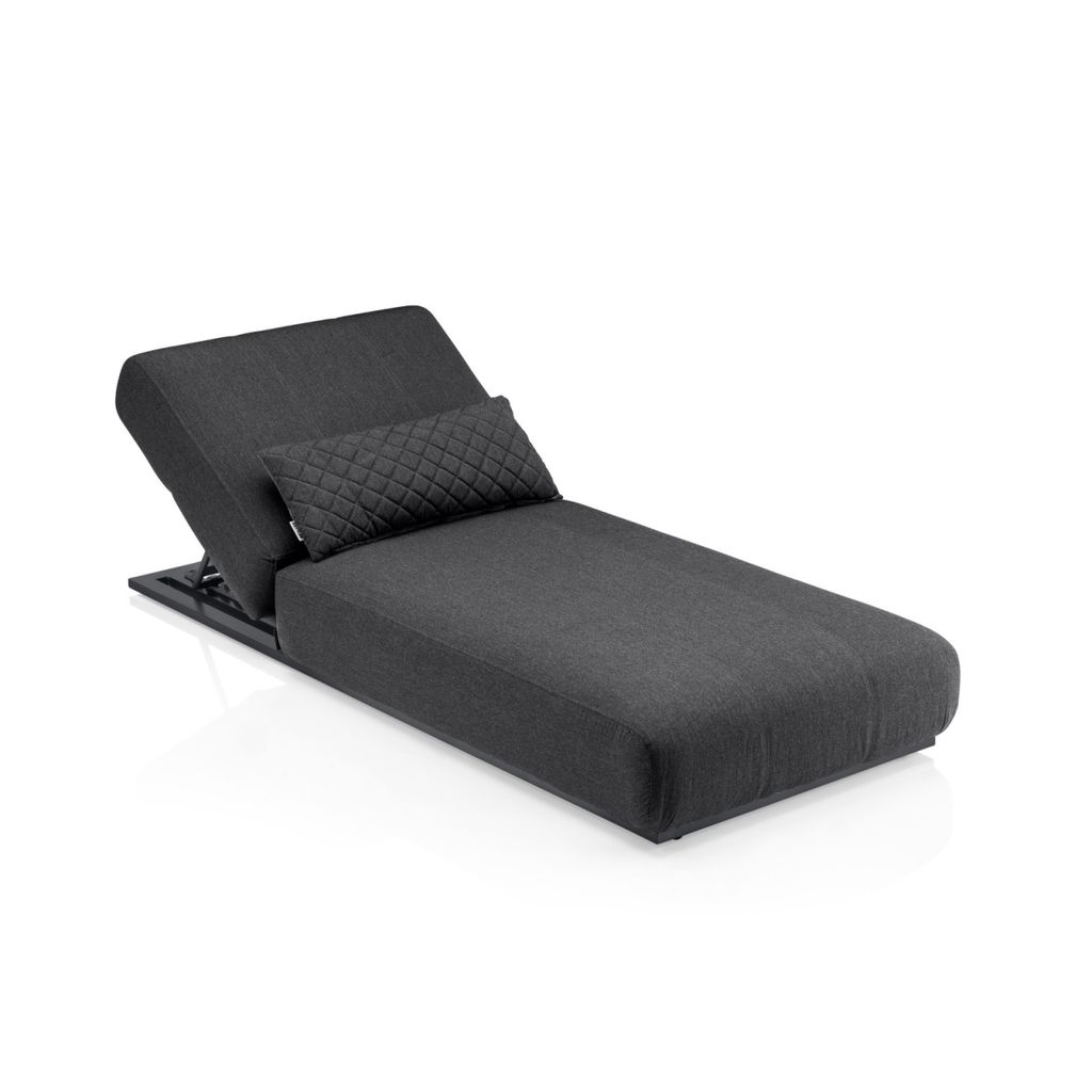 A dark gray chaise lounge with a small quilted pillow on a white background.