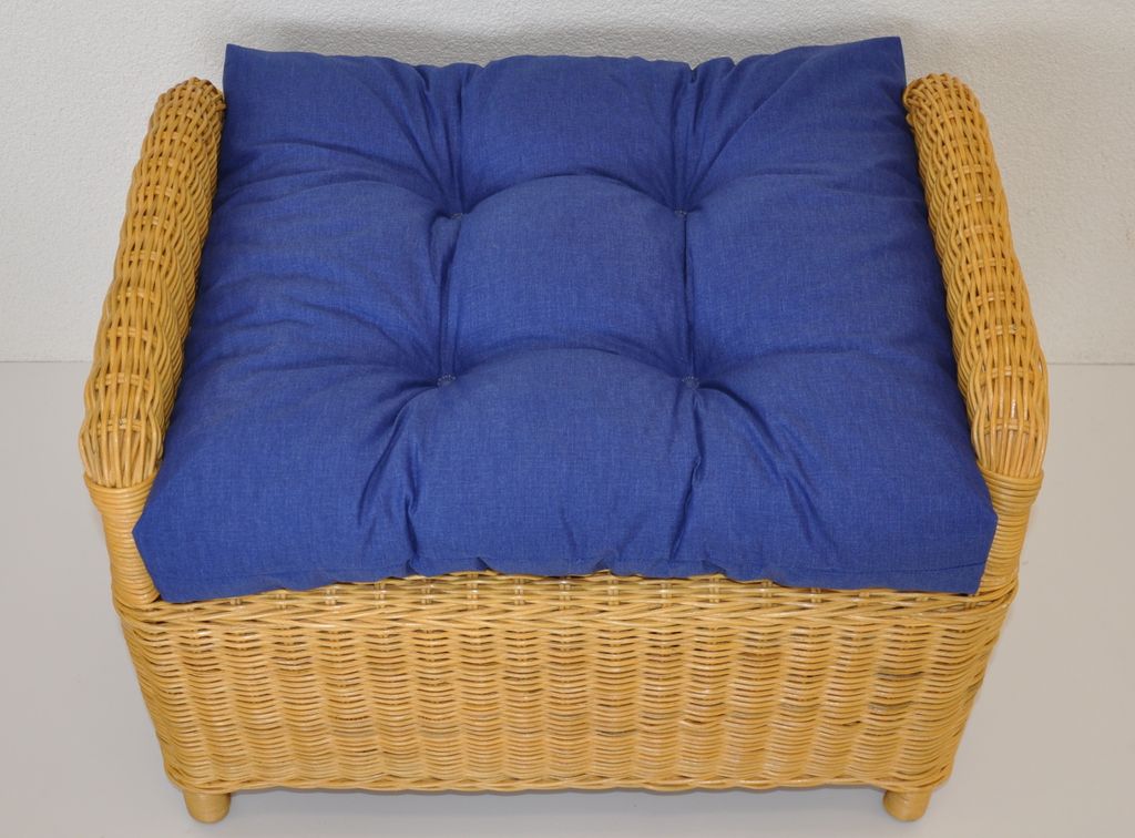 A blue cushion on a wicker ottoman.