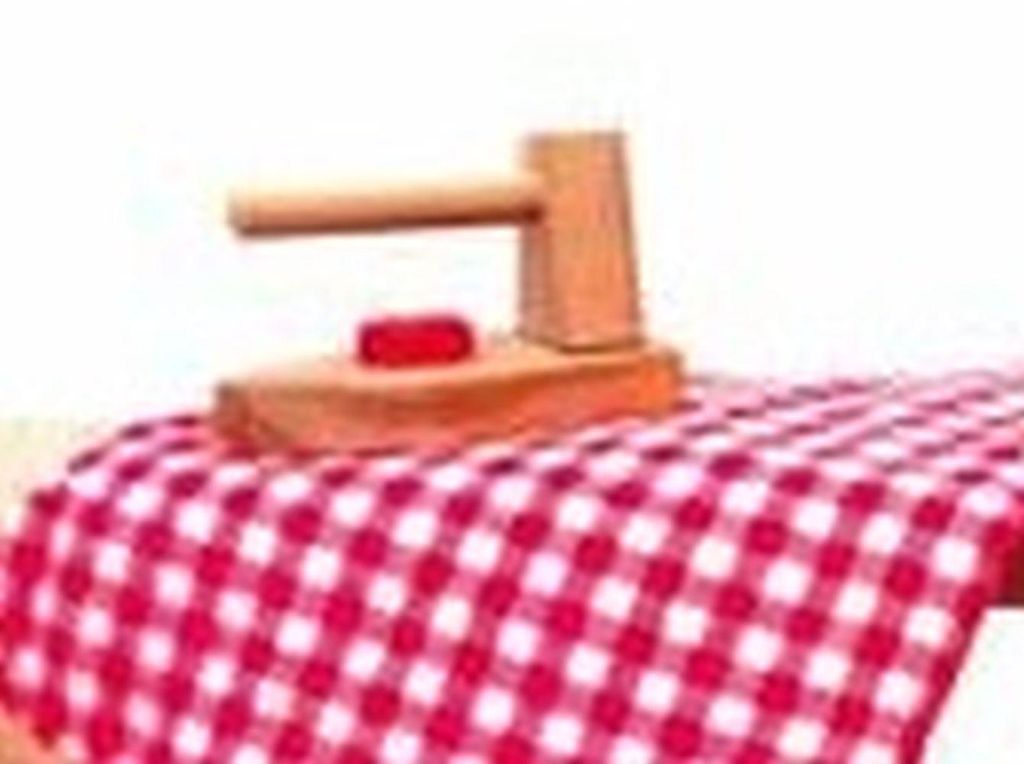 A wooden toy iron sits on a red and white checkered fabric, likely a tablecloth or ironing board cover.