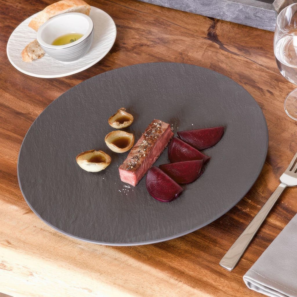 A plate of food with steak, beets, and onions on a wooden table.