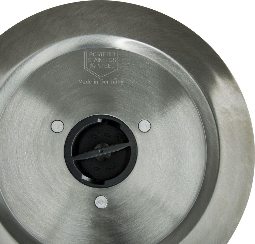 Close-up view of the bottom of a metal appliance, showing a central black component with blades and surrounding metal.