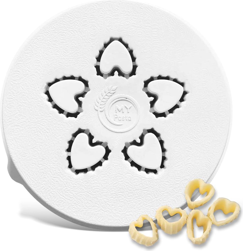 A white pasta maker accessory with heart-shaped cutouts, and several heart-shaped pasta pieces in the foreground.