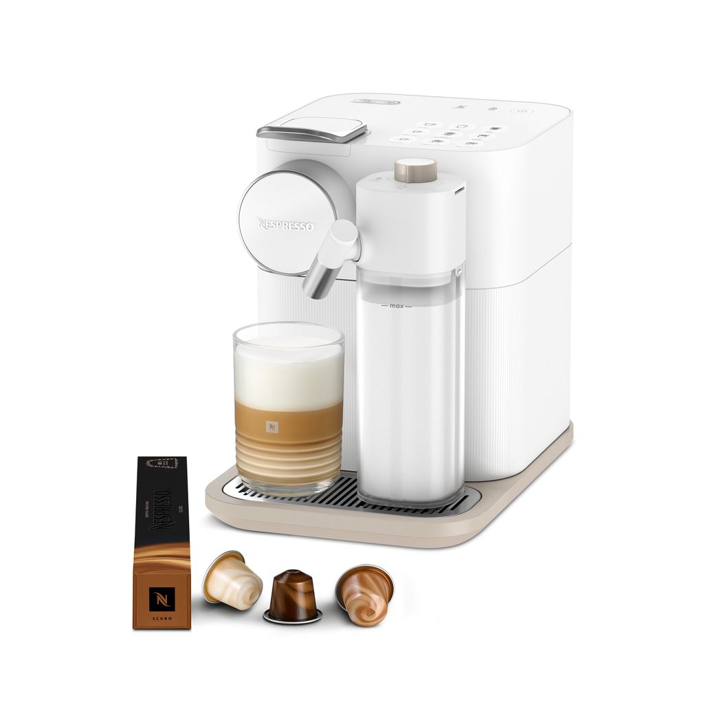 A white Nespresso coffee machine with a glass of coffee and coffee capsules.