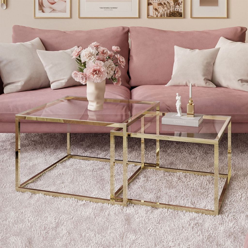 A set of two nesting gold-framed glass-top coffee tables in a pink living room.