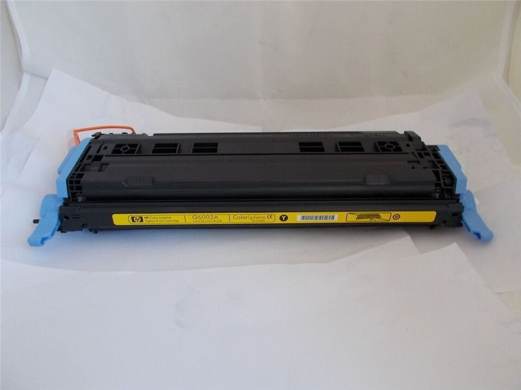 A yellow HP toner cartridge is shown on a white surface.