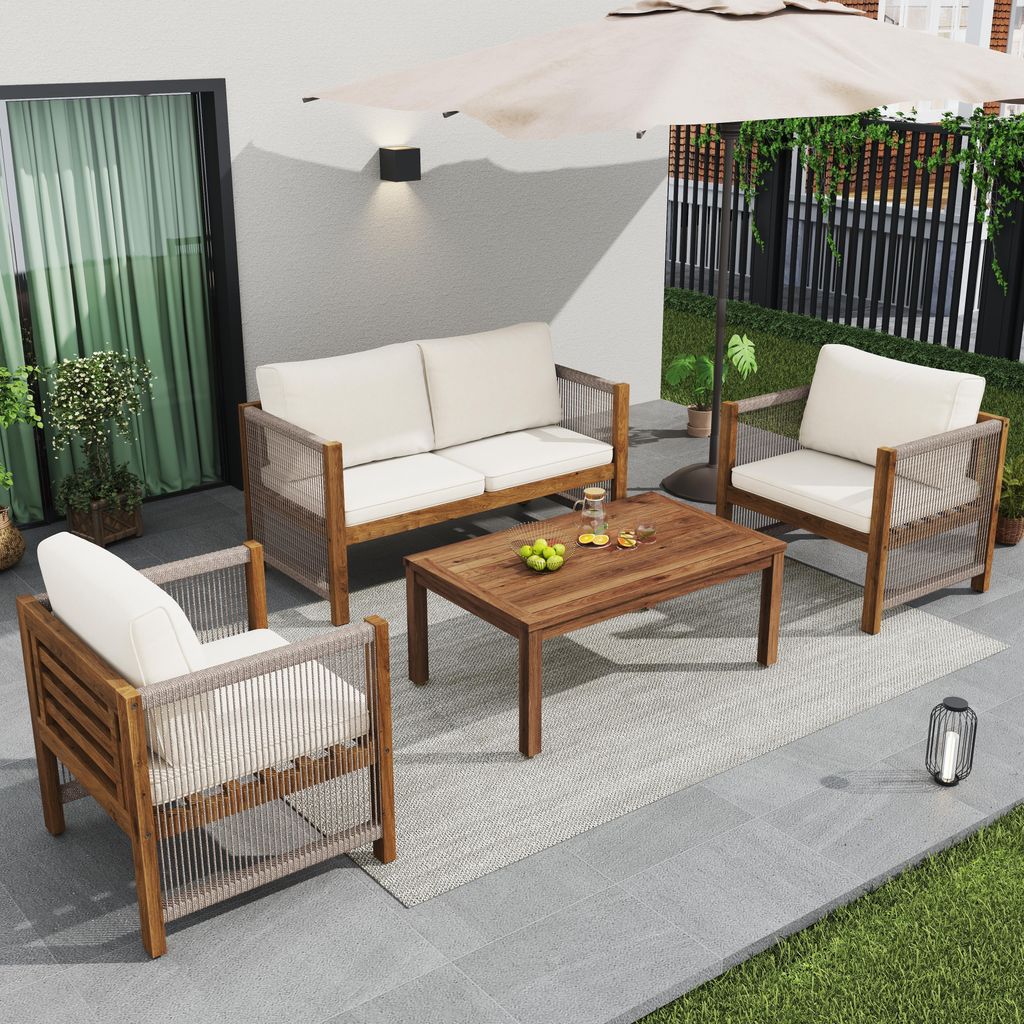 An outdoor patio set with a sofa, armchair, and coffee table, set up on a tiled patio with grass and a fence in the background.