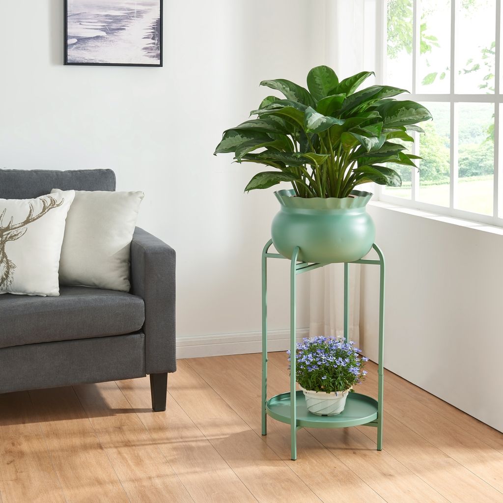 A living room scene with a sofa, a plant stand with two plants, and a framed picture on the wall.